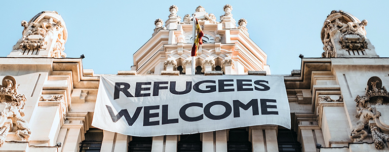 Refugees Welcome worded flag hanging from a parliamentary building in a European city.