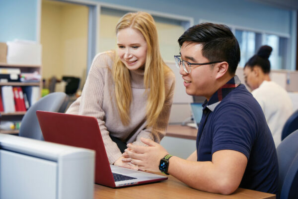 Decorative image. Two students view a laptop computer.