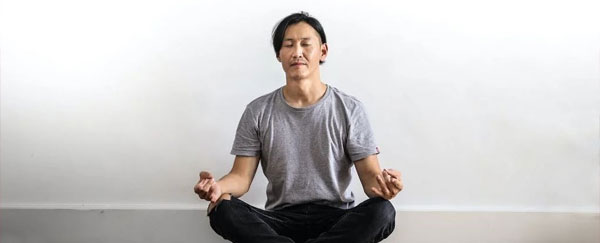 Photo of a man sitting on the floor while meditating