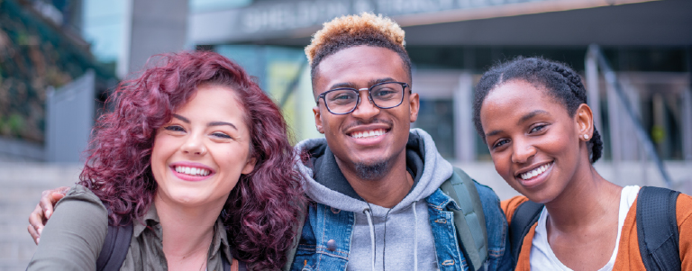 three students looking at the camera while smiling