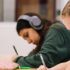 two students take notes side by side at a table.