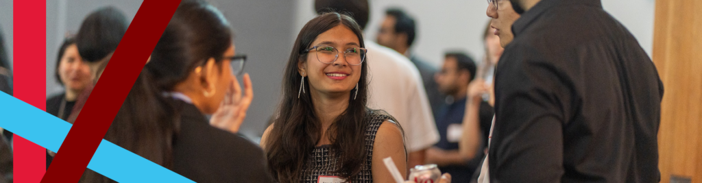 A young woman smiles while networking with other business professionals 