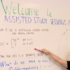 A photo of a peer-assisted study session. A student is at the front of the whiteboard pointing to text written on the board.