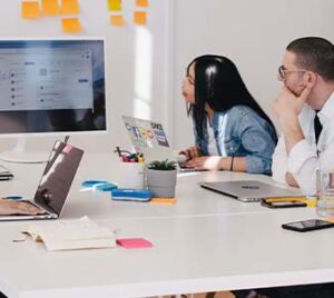 five people at a table look at a large screen together