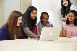 A group of students looking at a laptop screen.