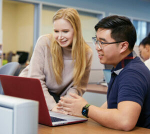 Photograph of two students looking at a computer. Decorative image.