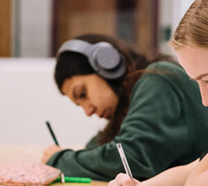 two people writing at a desk