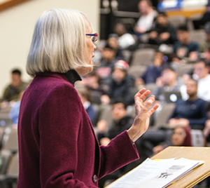 A professor stands at the podium delivering a lecture to students in Curtis Lecture Hall.