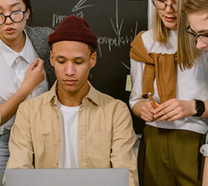 five students look at a laptop together